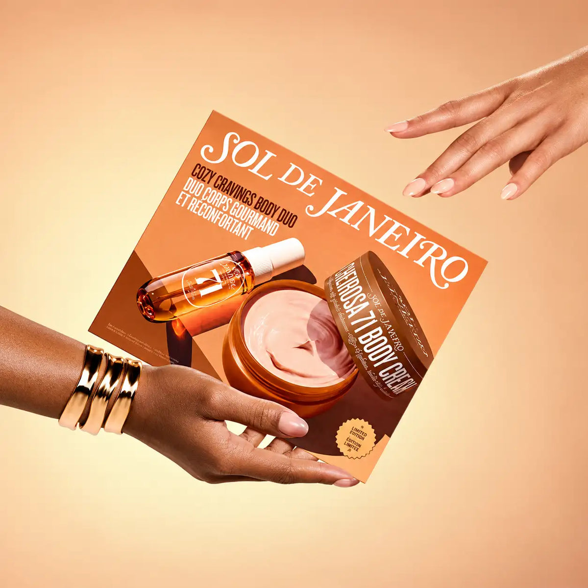 Emballage en carton orange pour un duo de soins pour le corps Sol de Janeiro, avec un flacon en verre ambré et un pot de crème rose.