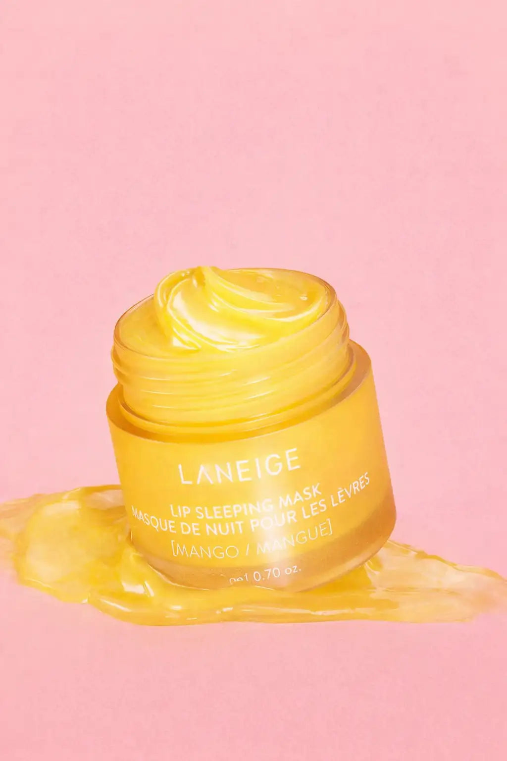 Un masque de nuit pour les lèvres à la mangue jaune vif dans un pot en verre transparent avec une étiquette blanche, présentant le nom de marque « laneige » et les détails du produit.